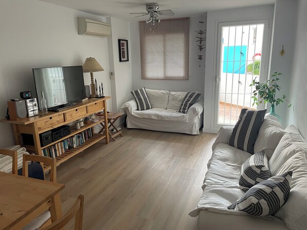 A living room with a wooden TV stand, a sofa, and a dining table. - Modern Apartment In The Heart Of The Old Town (Altea)