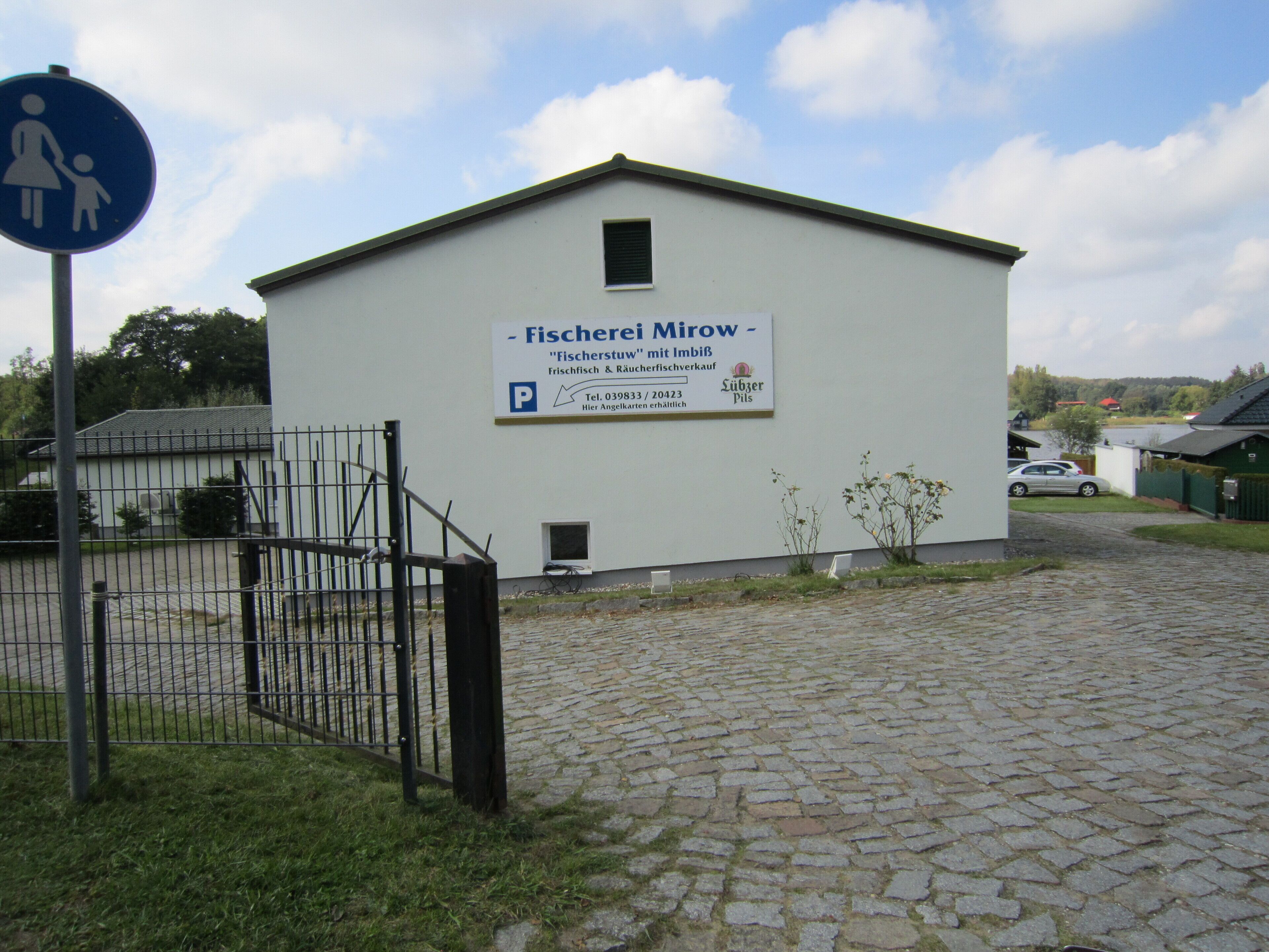 Um edifício com placa indicando ser uma área de pesca e um estacionamento.