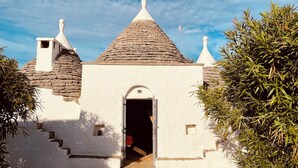 Il s’agit d’un bâtiment traditionnel doté d’un toit conique, d’une façade blanche et d’un escalier en pierre menant à une porte.