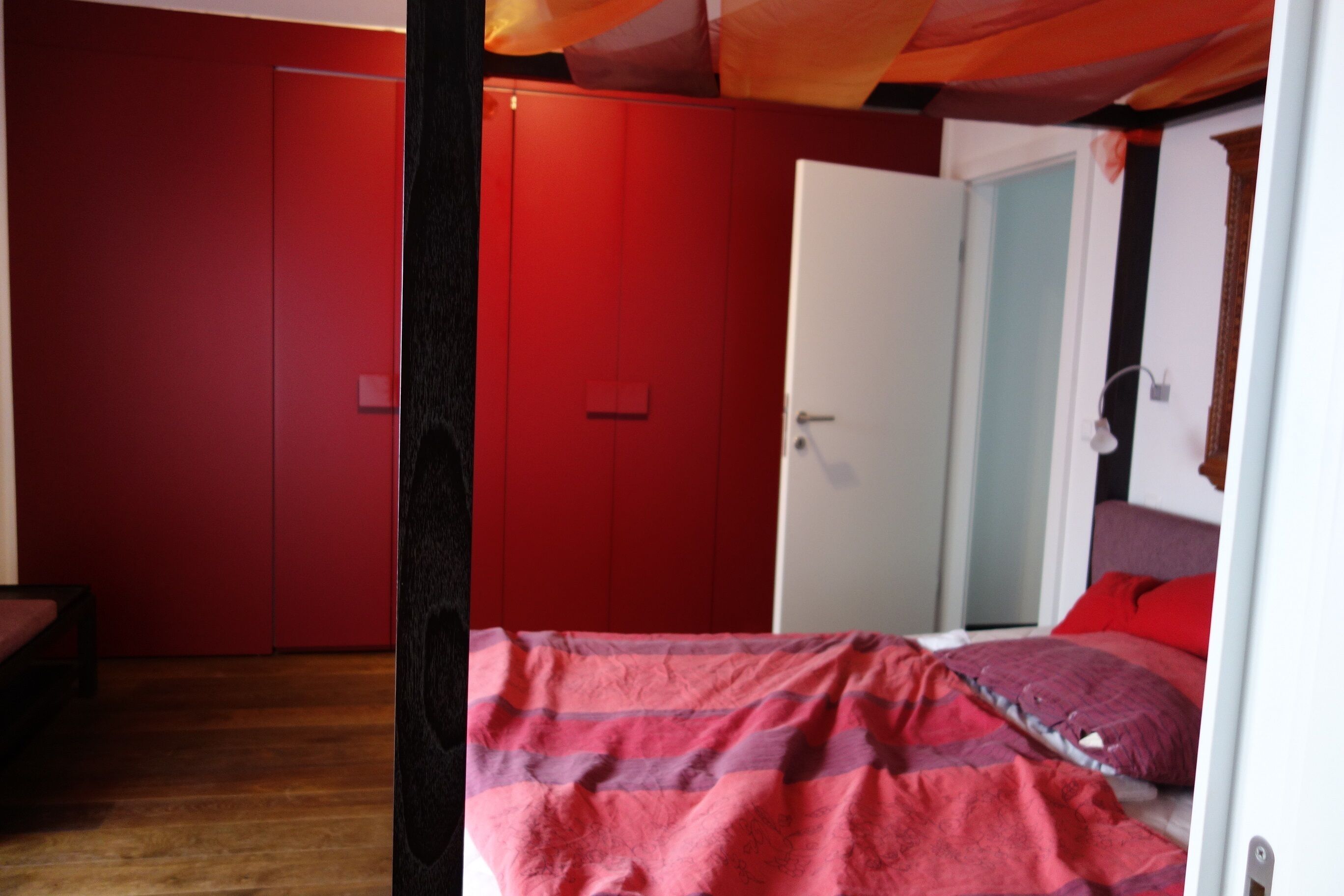 A room with a bed, a wardrobe, and a door.