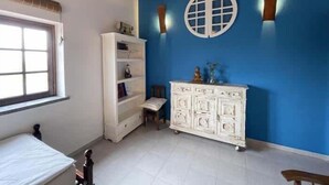 A room with a window, white furniture, a blue wall, and a decorative ceiling light. - Da Silva Surfcamp - Zambujeira Room (Lourinhã)