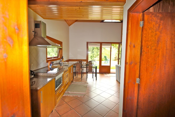 A kitchen with wooden cabinets, a stove, and a dining area with chairs and a table.
