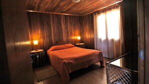 A wooden-paneled bedroom with a bed, two bedside lamps, and a window with curtains. - Quinta do Pântano is a calm and reserved place, with unique ambience and landscapes (Machico)