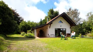 A house with a sloped roof, a covered porch, and a lawn. - Quinta do Pântano is a calm and reserved place, with unique ambience and landscapes (Machico)