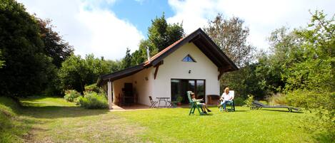 A house with a sloped roof, a covered porch, and a lawn.