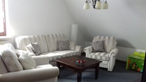 Ein Wohnzimmer mit einer Couch, zwei Sesseln, einem Couchtisch und einer Lampe.