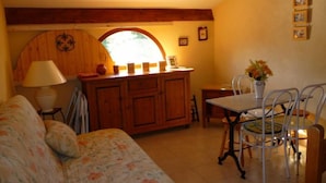 Un salon confortable avec un canapé, une table à manger et des chaises, un coin cuisine doté de meubles en bois et une fenêtre offrant une belle vue.