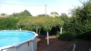 Une piscine avec une terrasse en bois et une petite table entourée de chaises.