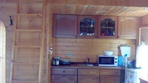 Una cocina compacta con armarios de madera, un microondas y un refrigerador.