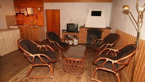 A cozy room with wicker chairs, a glass-top coffee table, a fireplace, and a television. - 4 lovely apartments on beautiful place in mountains in tourist´s and ski area (Bedrichov)