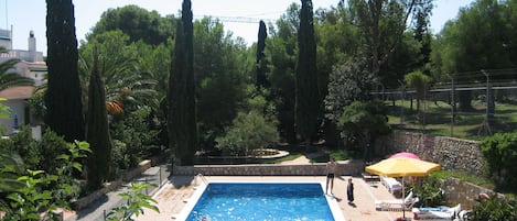 A swimming pool surrounded by trees and a stone wall.