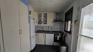A compact kitchen with white cabinets, a black tiled floor, and a window with blinds. - Apartment/ flat - Playa de Xeraco - XERACO (Xeraco)