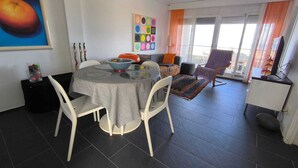 A dining area with a round table, chairs, and a colorful abstract painting on the wall. - Apartment/ flat - Playa de Xeraco - XERACO (Xeraco)
