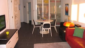 A modern living room with a flat-screen TV, a red sofa, and a dining area with a table and chairs. - Apartment/ flat - Playa de Xeraco - XERACO (Xeraco)
