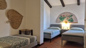 A room with two single beds, a wall-mounted fan, and a woven basket.