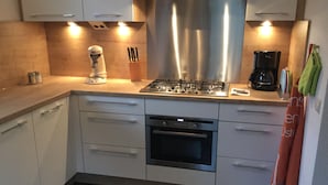 Uma cozinha moderna com eletrodomésticos de aço inoxidável, armários brancos e forno embutido.