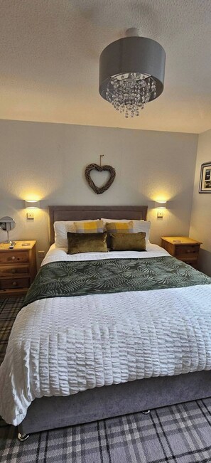 Une chambre à coucher avec un lit, deux tables de chevet, un décor mural en forme de cœur et un lustre.
