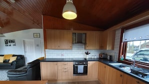 Et moderne køkken med træskabe, en sort bordplade og en hængende lampe.