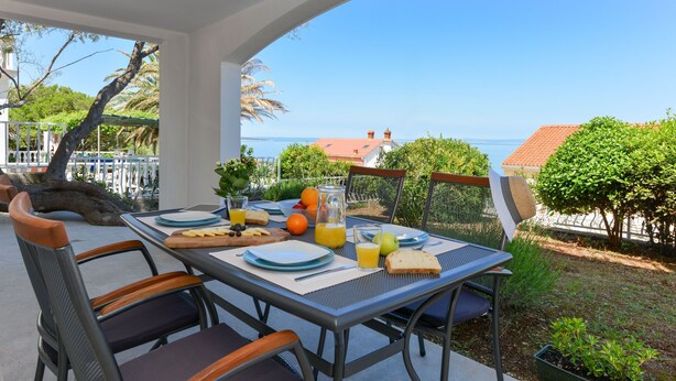 An outdoor dining area with a table set for breakfast, overlooking a scenic view of the sea. - Apartment Mare with beautiful sea views (Lun)