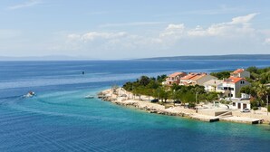 A coastal town with buildings along the waterfront, clear blue sea, and a boat in the water. - Apartment Mare with beautiful sea views (Lun)