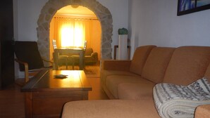 Una sala de estar acogedora con un arco de piedra que conduce a un comedor, una mesa de centro de madera y un sofá color beige.