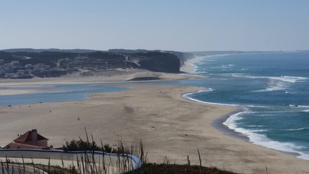 Un paisaje costero con una playa arenosa, un acantilado rocoso y una vista despejada del océano.