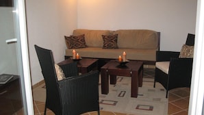 Een gezellige zithoek met een bank, twee fauteuils en een salontafel, elk voorzien van een kaars.