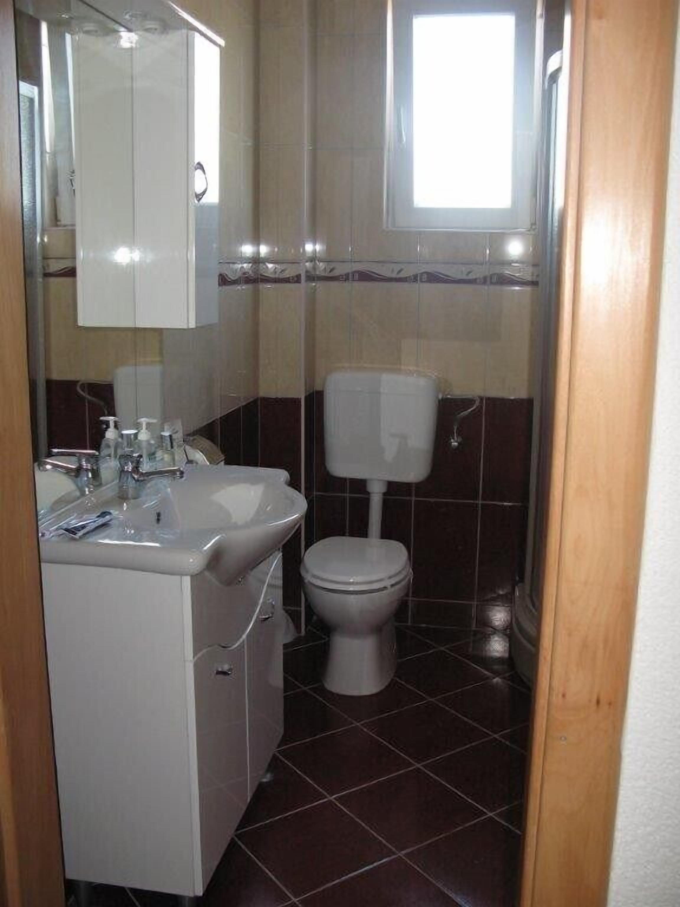 A small bathroom with a white sink, mirror, and toilet.