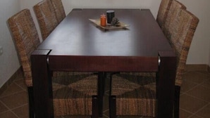 Een eetruimte met een rechthoekige tafel, zes stoelen, een hanglamp en een raam met uitzicht.