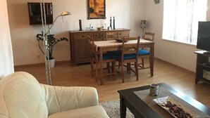 A living room with a sofa, a dining table with chairs, a TV, and a painting on the wall. - Over the rooftops of the historic old town, center in the pedestrian zone (Konstanz)