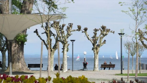 A park with benches, trees, and a view of the sea. - Over the rooftops of the historic old town, center in the pedestrian zone (Konstanz)