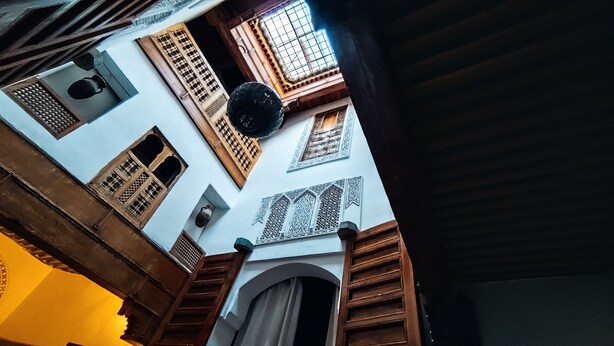 Een smalle steeg met traditionele architectuur, waaronder houten deuren en ramen met ingewikkelde rasterwerkdecoraties.