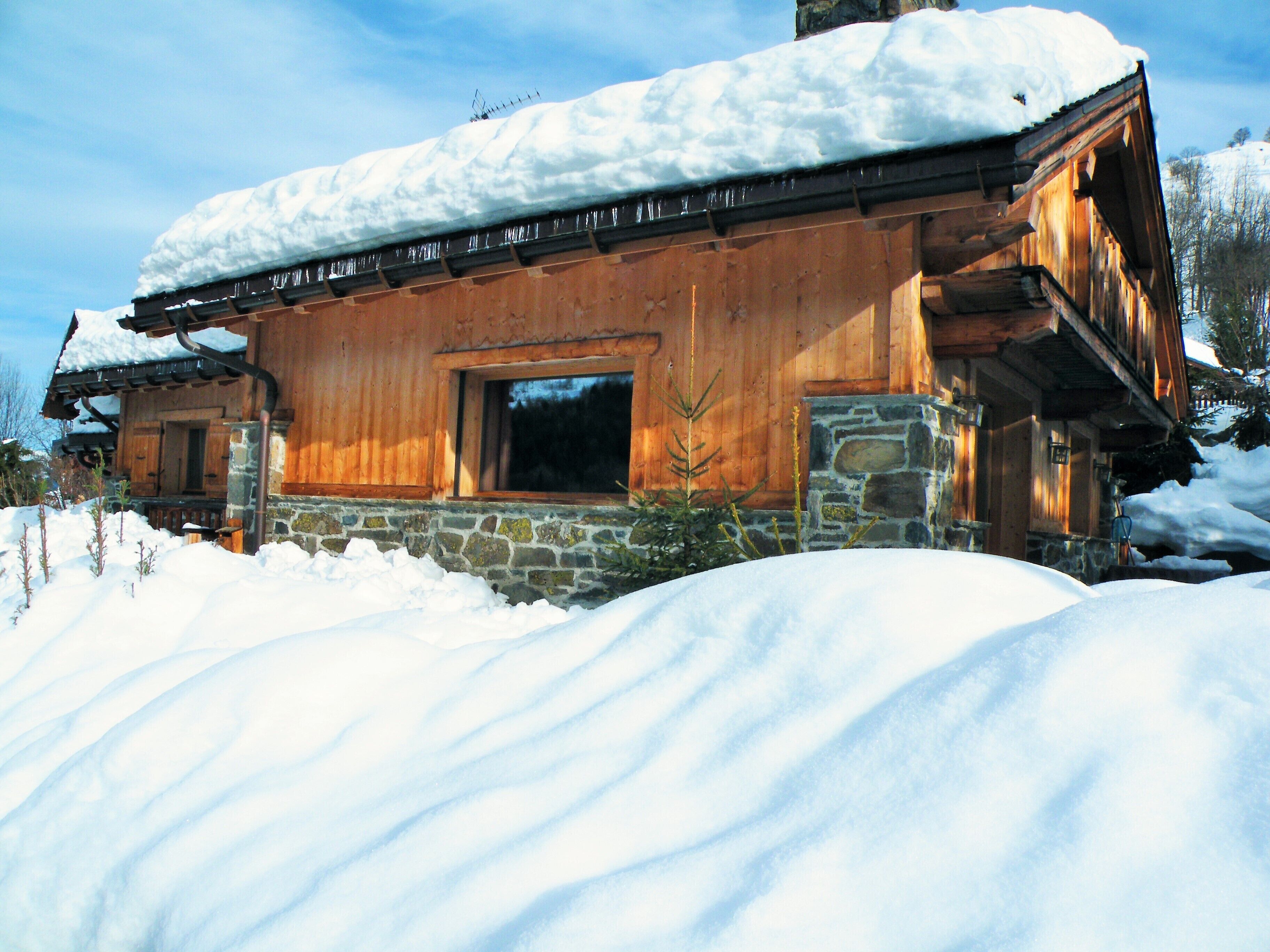 A wooden cabin with a stone foundation, surrounded by snow.