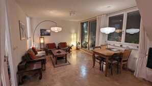 A spacious living room with a wooden floor, a dining area with a wooden table and chairs, and a large window with curtains. - Over the roofs of Berlin with lift and a great view at the TV tower (Berlin)