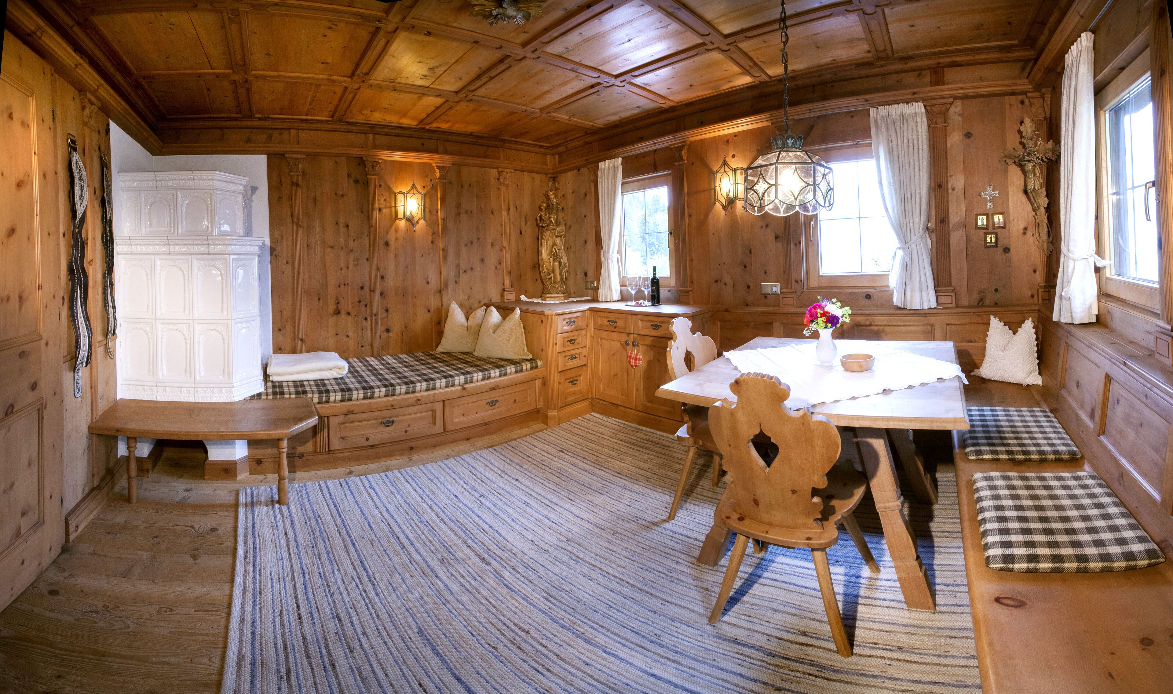 Ein gemütliches Blockhaus-Interieur mit einem Holzespeisetisch, Sitzbänken und einer integrierten Bank mit Staufächern.