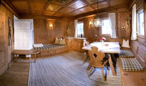 A cozy cabin interior with a wooden dining table, bench seating, and a built-in bench with storage drawers.