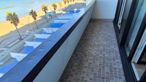 A balcony with a tiled floor, a view of a beach with palm trees, and a pool area. - Termoli 10 meters from the sea (Termoli)