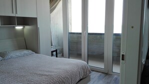 A bedroom with a bed, a chair, a sliding glass door to a balcony, and a ceiling light. - Termoli 10 meters from the sea (Termoli)
