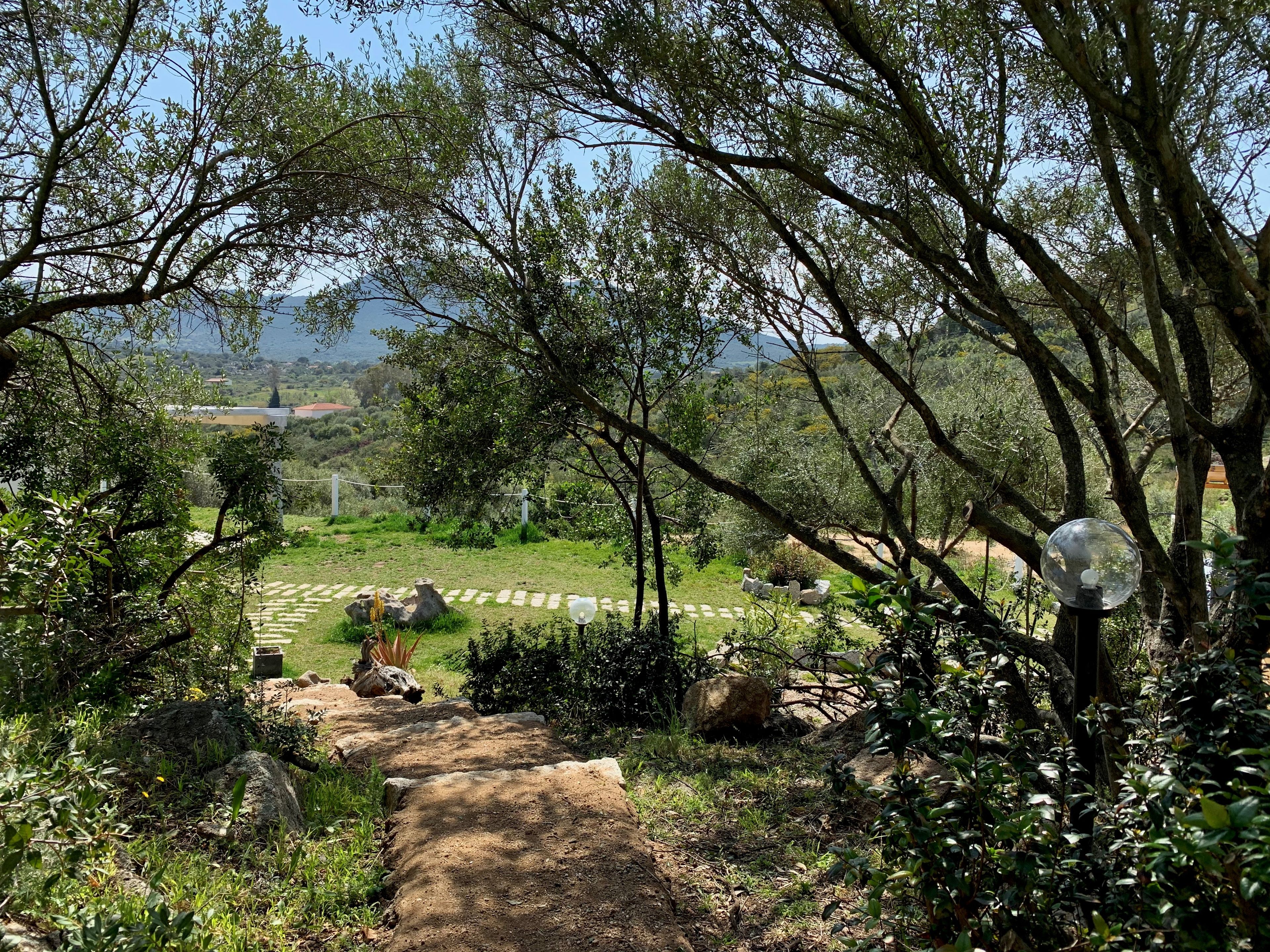 A garden path leading to a seating area with a view of a distant landscape.