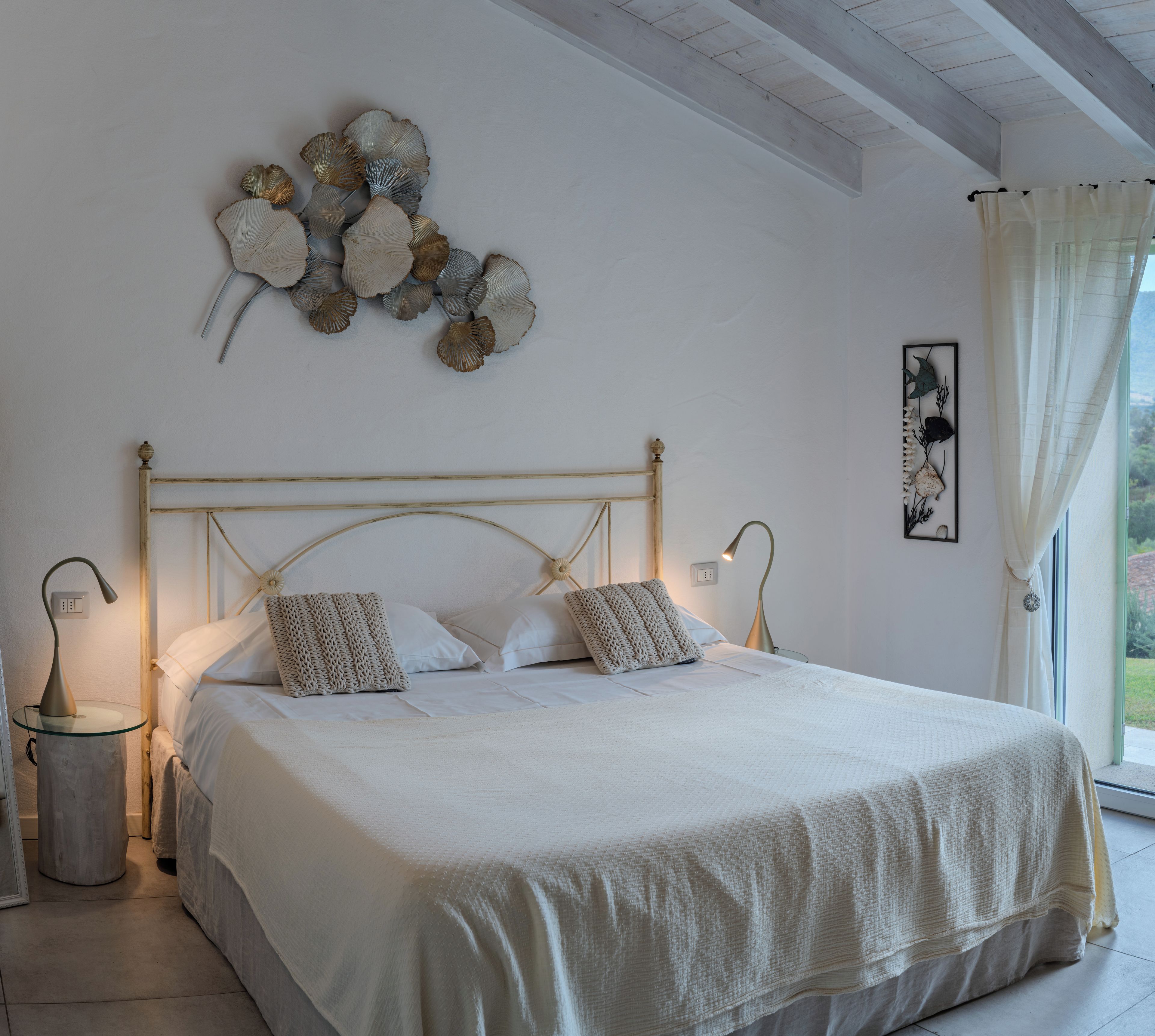 Une chambre à coucher avec un grand lit, deux tables de chevet, une lampe fixée au mur et un élément décoratif mural.