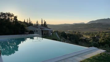 Une maison moderne avec une piscine, entourée de verdure et avec des montagnes en toile de fond.
