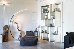 A modern living room with a curved floor lamp, a bookshelf, a bean bag, and a coffee table. - La Casa di Alice Smeralda (Olbia)