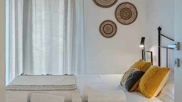 A bedroom with a bed, pillows, blankets, a bedside table, and wall decor.