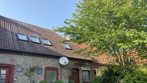 A brick building with a tiled roof, a satellite dish, and a small garden area with a table and chairs. - North Sea vacation right before SPO; 6-8 people, large garden apartment skipper - (Tating)