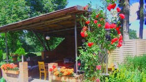 A covered outdoor seating area with brick planters and a wooden chair. - Apartment in quiet location (Frankenfeld-Bosse)