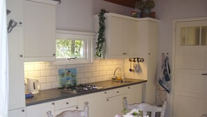 Une cuisine de taille réduite avec des meubles blancs, une cuisinière à gaz, un évier et une fenêtre.