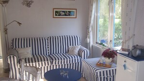 Une pièce avec un canapé à rayures, une petite table ronde et une fenêtre avec des rideaux.