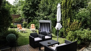 Uma área de pátio ao ar livre com móveis de vime, uma mesa e um guarda-sol.
