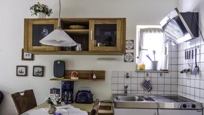 Uma cozinha compacta com armário de madeira, luminária pendente, pia e fogão.