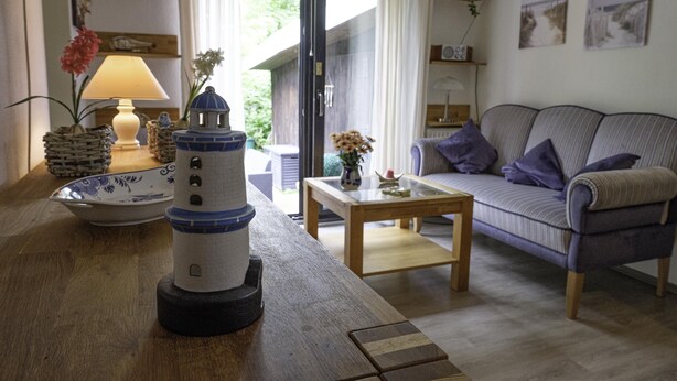 Uma sala de estar acolhedora com uma mesa de centro de madeira, um sofá e uma miniatura decorativa de farol.